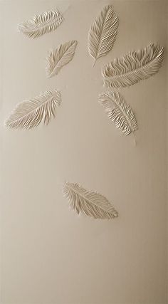 four metal leaves are hanging on the wall