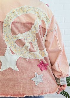 the back of a woman's pink jacket with embroidered letters and stars on it