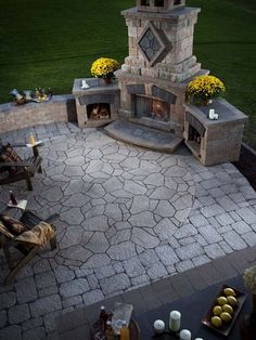 an image of a fire place in the middle of a patio with chairs around it