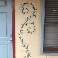 the door is painted with flowers and vines on it's side, next to a window