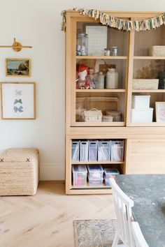 a wooden bookcase filled with lots of books next to a white chair and table