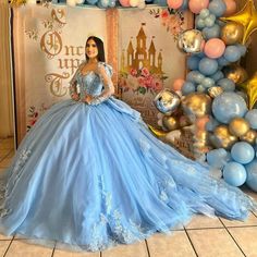 a woman in a blue dress standing next to balloons