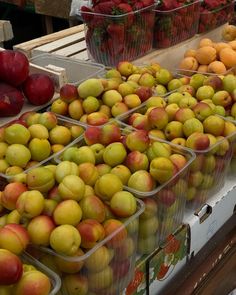 apples and strawberries are on display in plastic containers at the produce section of a grocery store