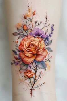 an orange rose tattoo on the side of a woman's leg with purple flowers and leaves