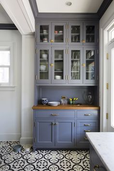 a kitchen with gray cabinets and black and white floor tiles