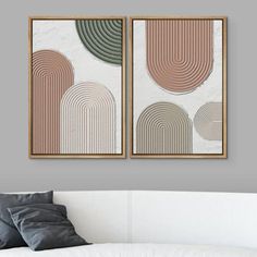 two framed art prints on the wall above a white couch