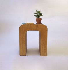 a small wooden stool with a potted plant on top