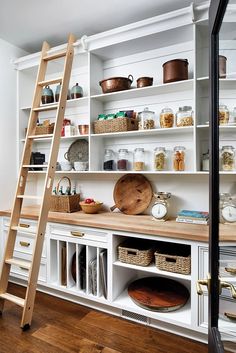 a kitchen with white cabinets and shelves filled with items