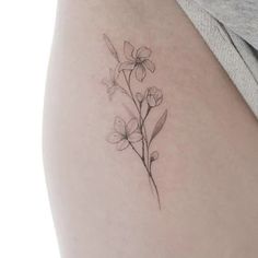 a woman's thigh with a small flower tattoo on the back of her leg