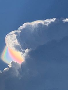 a rainbow appears in the clouds as it shines brightly against a bright blue sky