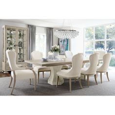 a dining room table with white chairs and a chandelier