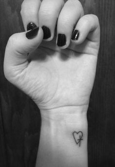 a woman's hand with a small heart tattoo on it