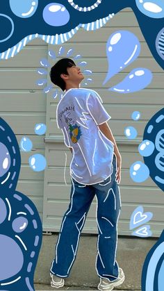 a young man standing in front of a wall with blue bubbles on it's side