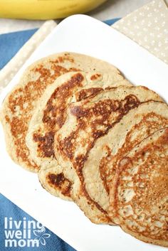 four pancakes on a white plate next to a banana