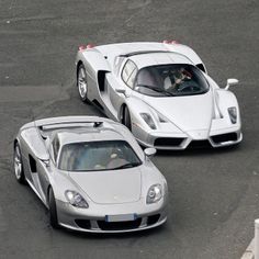 two white sports cars driving down a race track