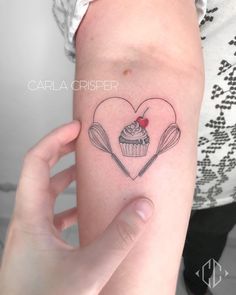 a woman holding up her arm with a cupcake and spoons tattoo on it