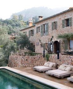 an outdoor swimming pool with chaise lounges next to it and stone buildings in the background