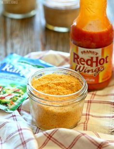 a jar of hot sauce sitting on top of a table next to a bottle of ketchup