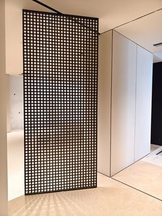 a room divider made out of black and white squares in the middle of an empty room