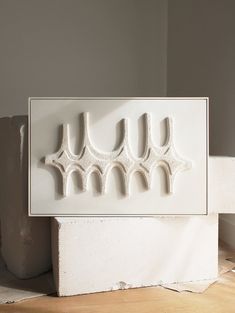 a white sculpture is sitting on the floor next to a cement block and some concrete blocks