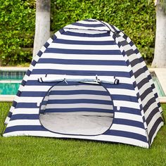 a blue and white striped tent sitting on top of grass next to a swimming pool