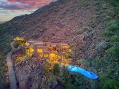 an aerial view of a home in the mountains at dusk with a pool and hot tub