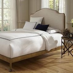 a white bed sitting on top of a hard wood floor next to two small tables