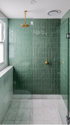 a green tiled bathroom with a shower head