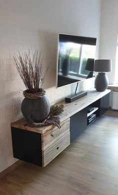 a flat screen tv sitting on top of a wooden shelf in a living room next to a lamp