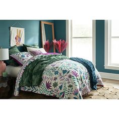 a bed in a room with blue walls and green comforter on top of it