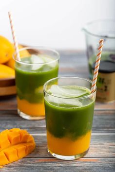 two glasses filled with green smoothie next to sliced mangoes