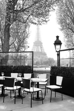 black and white photograph of tables with chairs in front of the eiffel tower