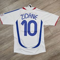 a white and blue soccer jersey with the number 10 on it sitting on a wooden floor