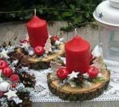 three red candles sitting on top of wooden logs next to pine cones and other decorations