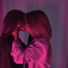 two women are kissing in front of a purple background