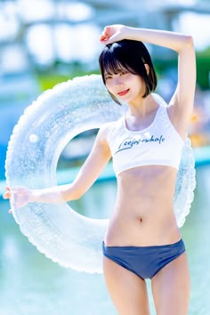 a woman in a bathing suit holding an inner tube and posing for the camera with her hands behind her head