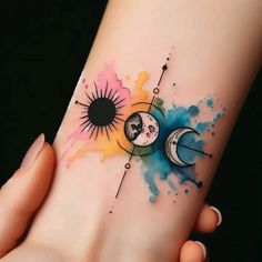 a woman's arm with a watercolor tattoo on it and the sun and moon