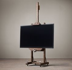 an easel with a flat screen on it in front of a gray wall and wooden floor