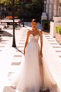 a woman in a wedding dress standing on the sidewalk