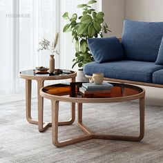 two coffee tables sitting next to each other on top of a carpeted floor in front of a blue couch