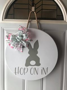 a door hanger that says hop on in with a bow hanging from it's side