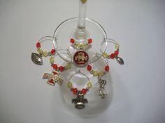 a wine glass holder with charms on it and a bottle in the middle that has a red bead around it