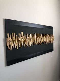 a black and gold wall hanging on the side of a white wall with clothes pins attached to it