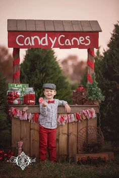 a little boy standing in front of a candy cane stand