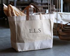 a tote bag sitting on top of a floor next to a basket filled with clothes