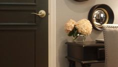 a vase with flowers sitting on top of a small table next to a black door