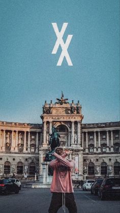 a man standing in front of a building with the letter x above him and an arrow over his head