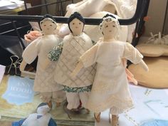 three dolls are standing next to each other in front of a bed with sheets on it