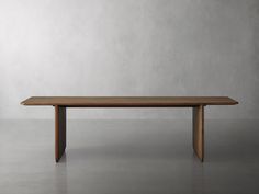 a wooden table sitting on top of a cement floor next to a white wall in an empty room