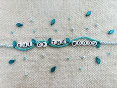 the word out of the woods spelled with beads